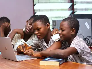 A group of Ghanaian students gathered around a laptop computer