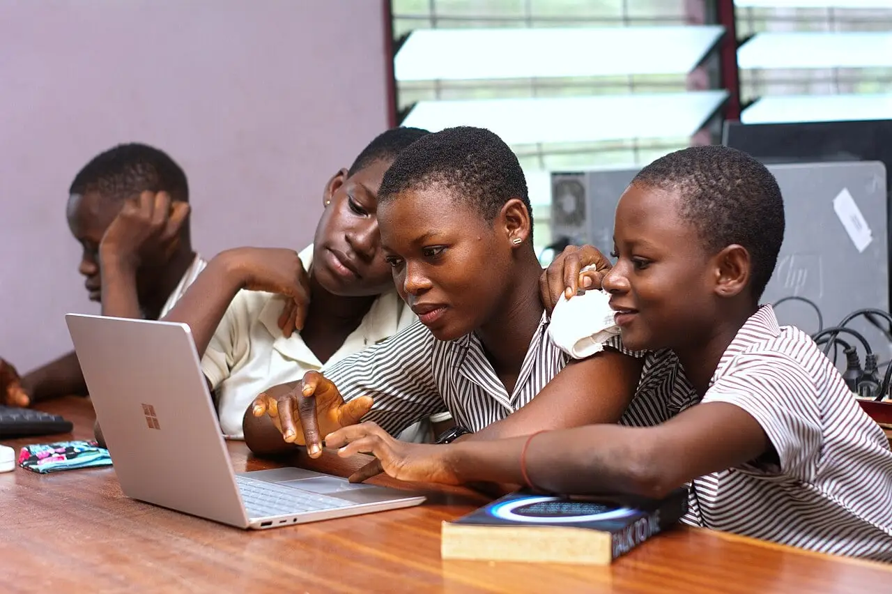 A group of Ghanaian students gathered around a laptop computer